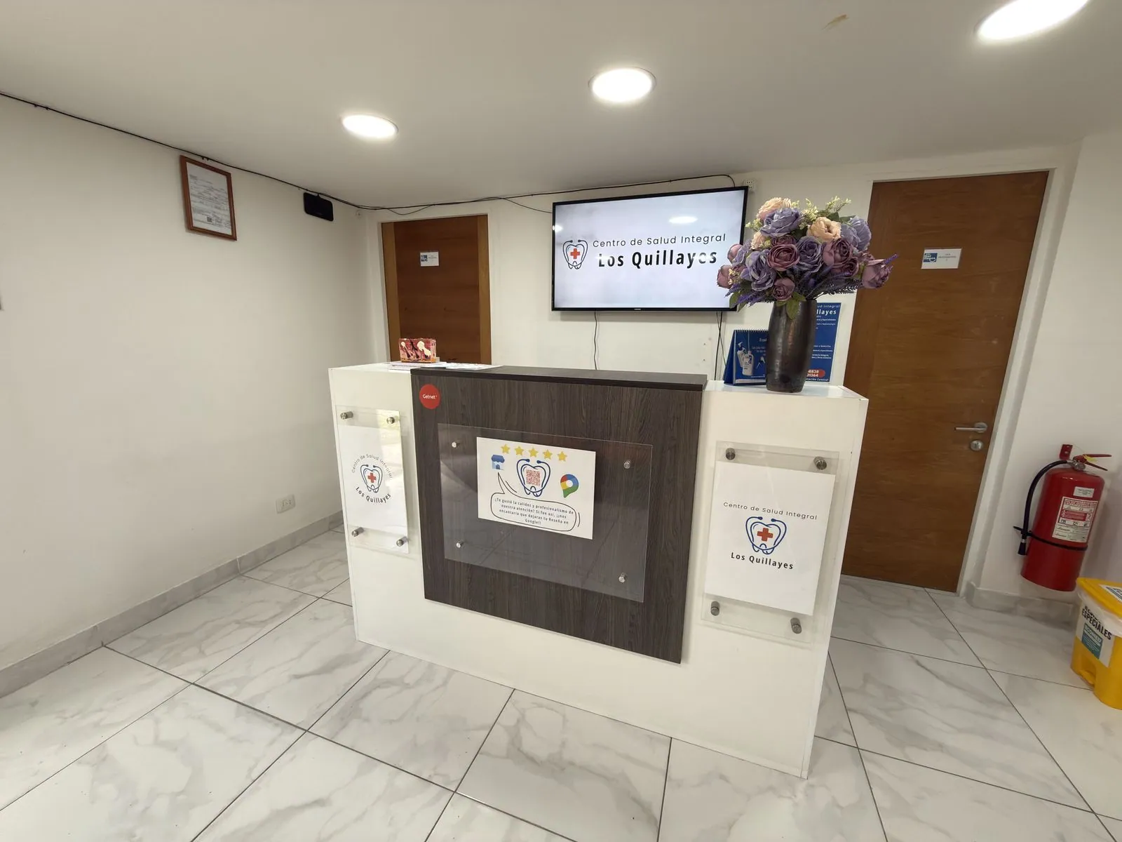 Mesón de recepción y pantalla con el logo del Centro de Salud Integral Los Quillayes